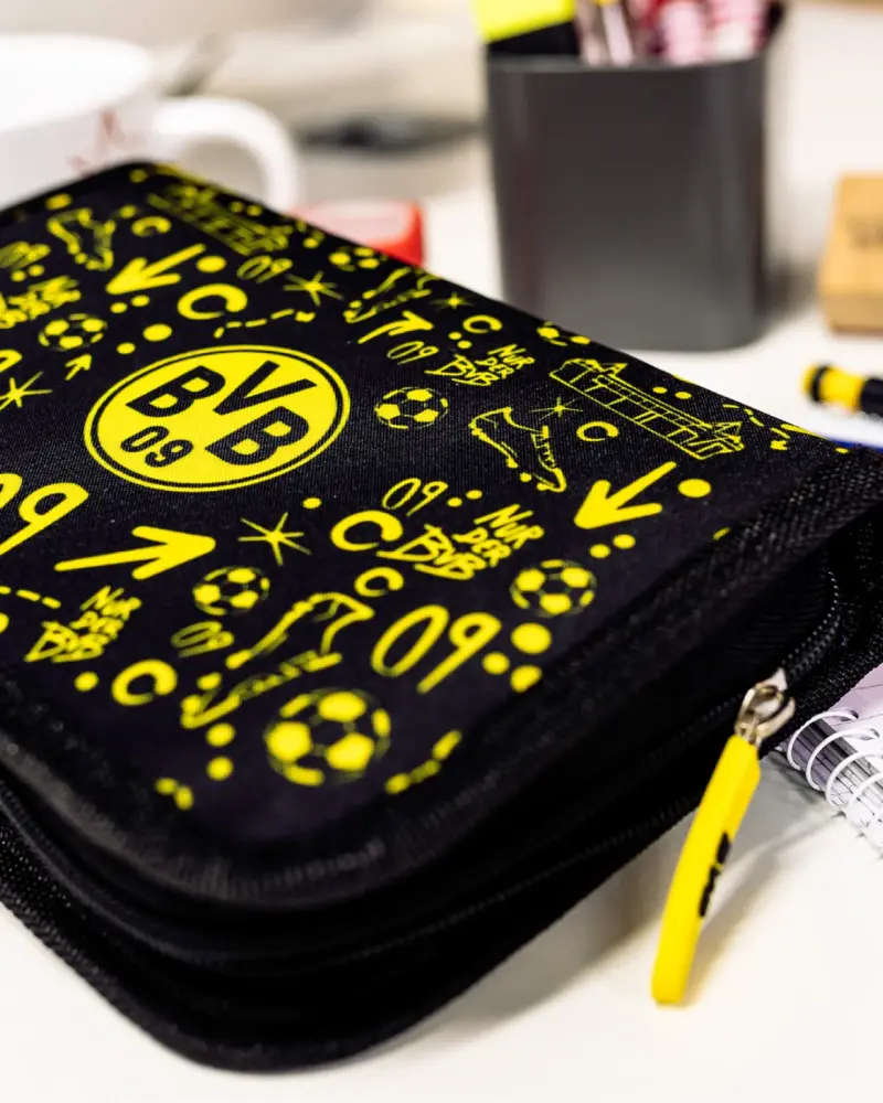 Schwarz-gelbes Federmäppchen mit Fußballmotiven auf einem Schreibtisch